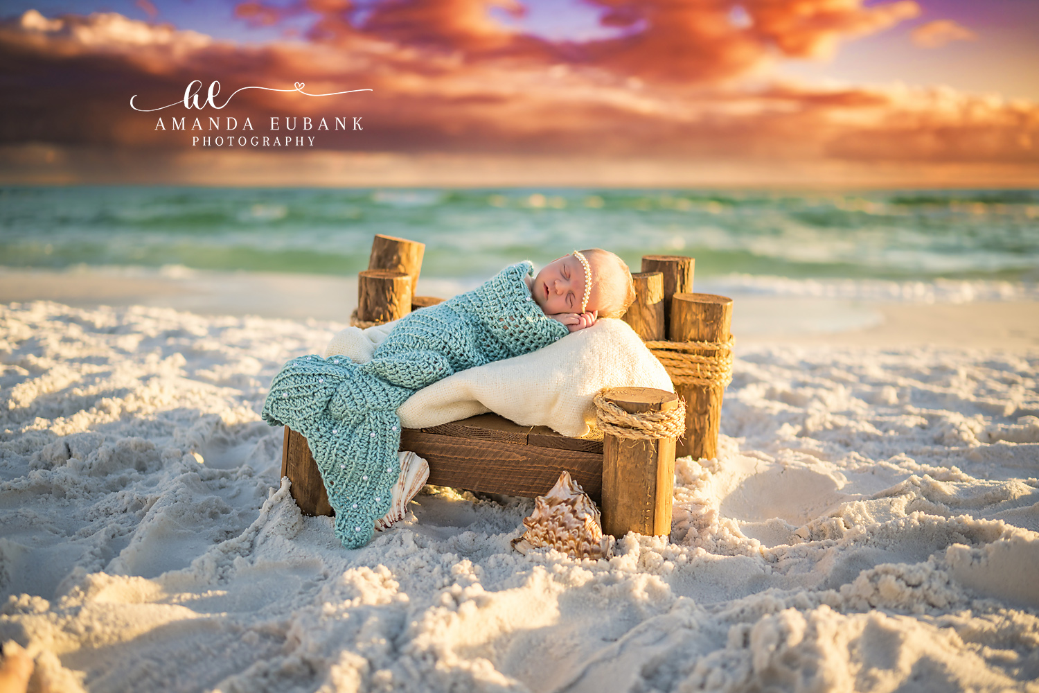Destin Newborn Photographer | Beach Mermaid Newborn Session Destin newborn photographer captures a sleeping baby in a teal mermaid tail on a log bed at sunset on a Destin beach.