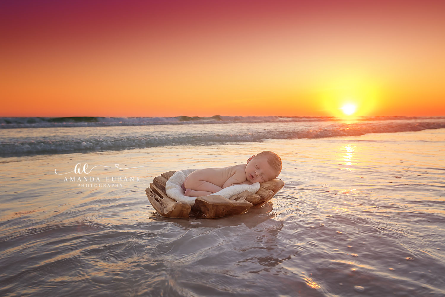 Destin Newborn Photographer | Driftwood Sunset Beach Newborn Session Destin newborn photographer captures sleeping baby in driftwood cradle floating in shallow Gulf surf at sunset in Destin, Florida.